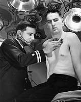 Photo # NH 98464:  Doctor examines a patient on board USS Columbus, April 1965.  Photographed by PH2 R.D. Fennell